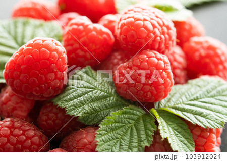 Fresh red raspberries with leaves macro shot Fresh red raspberries with leaves macro shot 103912024