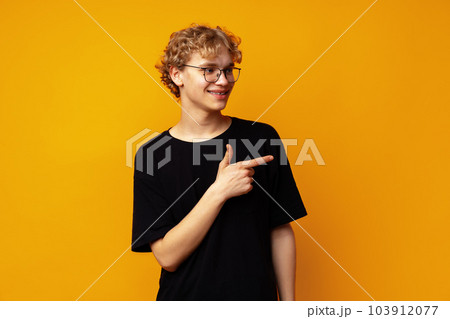 Handsome young man pointing finger to copy space on yellow banner background 103912077