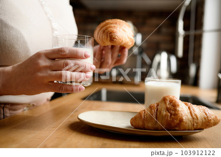 Girl has a breakfast with milk and croissants at kitchen 103912122