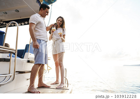 Young loving couple sitting on the yacht deck and drinking wine 103912228