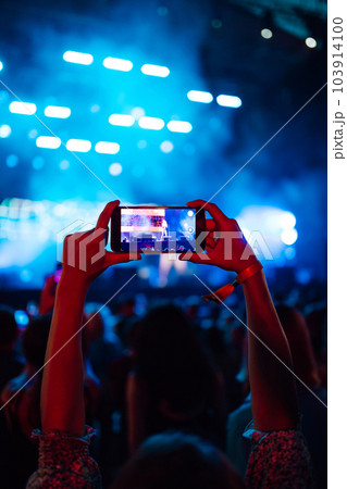 Hand with a phone records live music festival. People taking photographs with smart phone. Hand with a phone records live music festival. People taking photographs with smart phone. 103914100