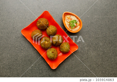 Traditional Egyptian dish Falafel with hummus served in Orange colored plate on Gray background Traditional Egyptian dish Falafel with hummus served in Orange colored plate on Gray background 103914863
