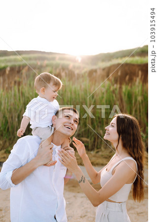 Cheerful young family with little baby boy spending time together on the beach. 103915494