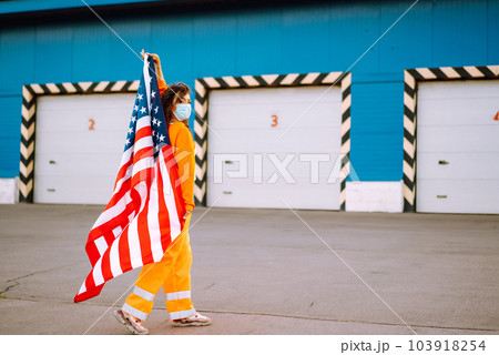 African American woman with medical face mask posing with american flag.The concept of preventing the spread of the epidemic. Covid-2019. African American woman with medical face mask posing with american flag.The concept of preventing the spread of the epidemic. Covid-2019. 103918254
