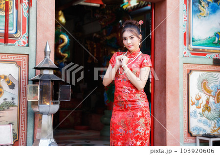 Chinese woman in a red cheongsam dress pay homage to Chinese god at shrine. Concept to celebrate Chinese New Year. Chinese woman in a red cheongsam dress pay homage to Chinese god at shrine. Concept to celebrate Chinese New Year. 103920606