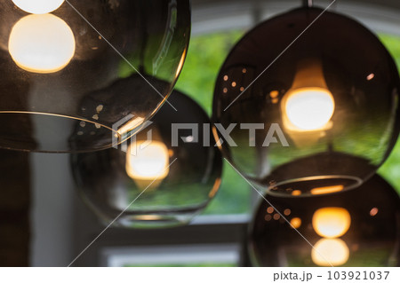 Round glass lampshades with  glowing tungsten lamps inside, close-up 103921037