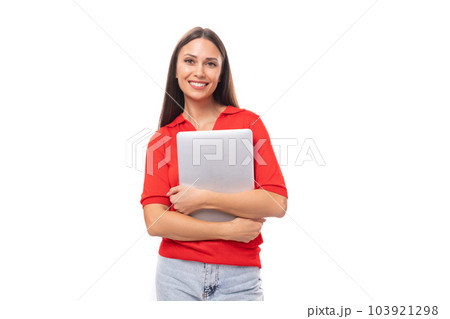 young brunette lady dressed in a red t-shirt holds a gray laptop in her hands on a white background young brunette lady dressed in a red t-shirt holds a gray laptop in her hands on a white background 103921298