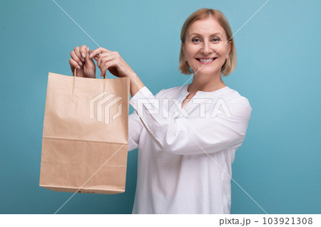 joyful mature woman holding craft brown shopping bag 103921308