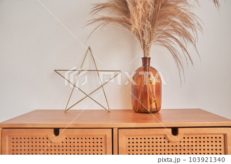 Decorative elements of the interior. with space to copy. Dried spikelets in a vase. Living room with a home decor in the form of a star and a vase with dried flowers. High quality photo Decorative elements of the interior. with space to copy. Dried spikelets in a vase. Living room with a home decor in the form of a star and a vase with dried flowers. High quality photo 103921340