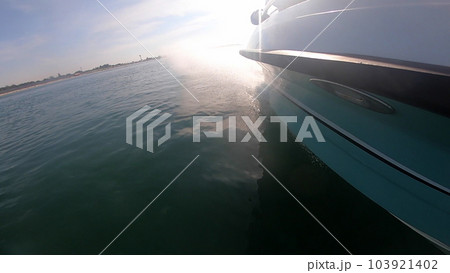 Motorboat swimming fast, jumping on sea surface of water on sunny summer day. View of side of boat. Lots of white splashes from moving of boat. Leisure relax travel transportation 103921402