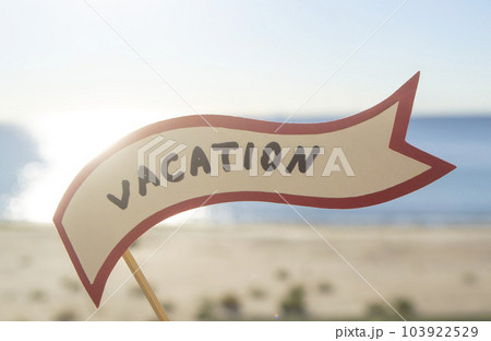Stick with paper speech bubble with words Vacation on background sea, sky, sandy beach on a sunny summer day. Text-balloons with text from letters. Concept, symbol, sign vacation travel tourism rest. Stick with paper speech bubble with words Vacation on background sea, sky, sandy beach on a sunny summer day. Text-balloons with text from letters. Concept, symbol, sign vacation travel tourism rest. 103922529