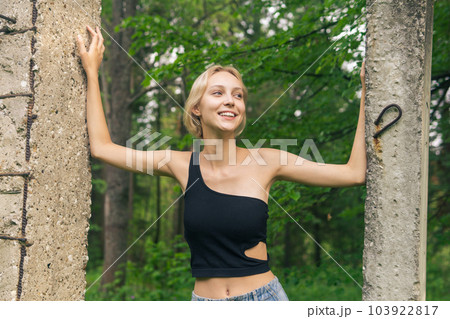 smiling young woman posing next to concrete piles among natural landscape 103922817