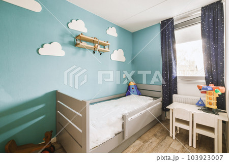 a child's room with blue walls and white furniture, including a small cribe bed in the corner 103923007