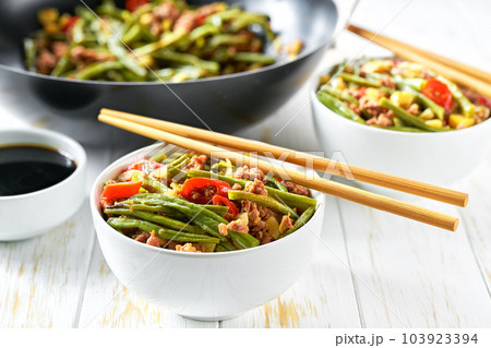 Spicy chinese sichuan stir-fried green beans in a wok with  garlic, red pepper and ginger, on a wooden table. 103923394