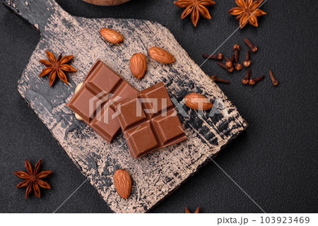 Delicious sweet milk chocolate broken into cubes on a wooden cutting board 103923469