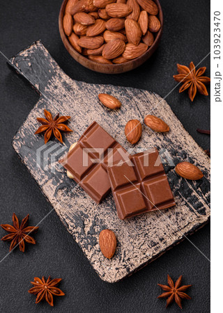 Delicious sweet milk chocolate broken into cubes on a wooden cutting board Delicious sweet milk chocolate broken into cubes on a wooden cutting board 103923470