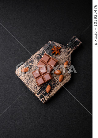 Delicious sweet milk chocolate broken into cubes on a wooden cutting board 103923476