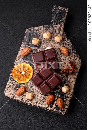 Delicious sweet black chocolate broken into cubes on a wooden cutting board 103923483