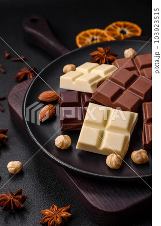 A mix of several types of delicious sweet chocolate broken into cubes on a black plate 103923515