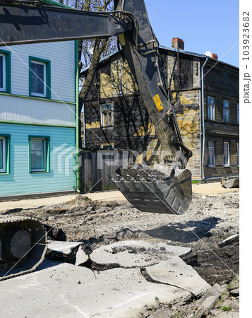 Crawler excavator with a bucket dismantle the asphalt before the reconstruction of the street 103923682