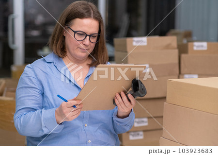 female entrepreneur working from home, using a laptop to manage her small business and package products for delivery or express shipping female entrepreneur working from home, using a laptop to manage her small business and package products for delivery or express shipping 103923683