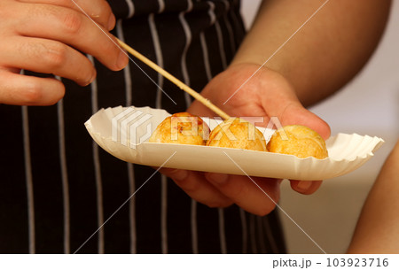 A chef sticks a portion of deep-fried dumplings into a paper box. A chef sticks a portion of deep-fried dumplings into a paper box. 103923716