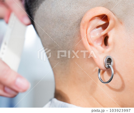 Close-up of a woman's ear with a small tunnel.  103923997
