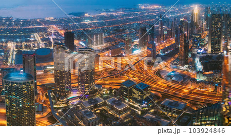 Aerial View Of Evening Night Scenic View Of Skyscraper In Dubai. Street Night Traffic In Dudai Skyline. Waterfront And Dubai Cityscape In Summer Evening Illuminations. Urban background. High quality Aerial View Of Evening Night Scenic View Of Skyscraper In Dubai. Street Night Traffic In Dudai Skyline. Waterfront And Dubai Cityscape In Summer Evening Illuminations. Urban background. High quality 103924846