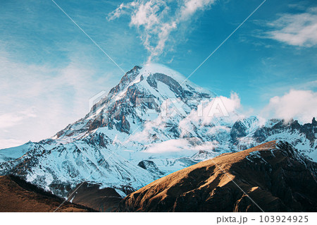 Georgia. Peak Of Mount Kazbek Covered With Snow. Amazing Georgian Nature Landscape In Winter Sunny Day. Amazing Bold Bright Blue Sky. Travel To Georgia 103924925