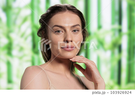 Beautiful smiling woman with fresh skin after using herbal facial cosmetics portrait. Attractive young skincare treatment model holding hand under chin and looking at camera 103926924