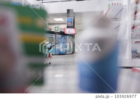 Selective focus of pharmacy counter desk filled with pharmaceutical products and computer, health space waiting for customers to come and buy pills. Drugstore shelves were stocked with drugs packages. 103926977
