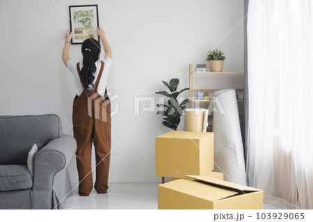 Woman decorating new home while moving in to new house or apartment. Woman decorating new home while moving in to new house or apartment. 103929065