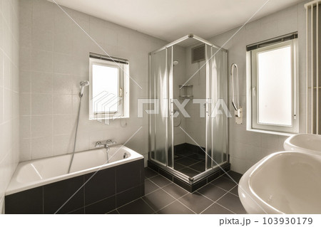 a modern bathroom with black and white tile flooring, large walk - in shower and free standing bathtub 103930179