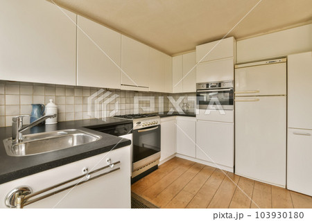 a kitchen with white cupboards and black counter tops on the counters in this photo is taken from the inside 103930180