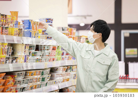 スーパーで買い物をする作業服姿の若い男性 103930183