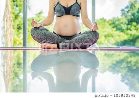 Young pregnant woman doing yoga exercises and meditating at home or yoga studio. Health care, mindfulness, relaxation and wellness concept 103930548