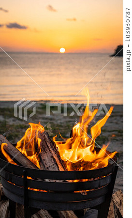 焚き火 焚き火台 炎 キャンプファイヤー 夕方 サンセット 海岸 夕焼け 屋外 コピースペース 夕日 103930787