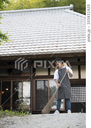 古民家や古い家の庭を掃除して手入れする男性	 103931920