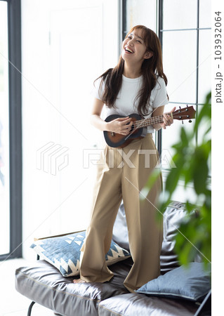 部屋でウクレレを弾く女性の写真素材 [103932064] - PIXTA