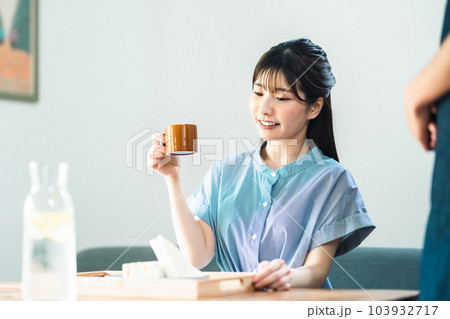 カフェでコーヒーを楽しむワンピース姿の若い女性 103932717