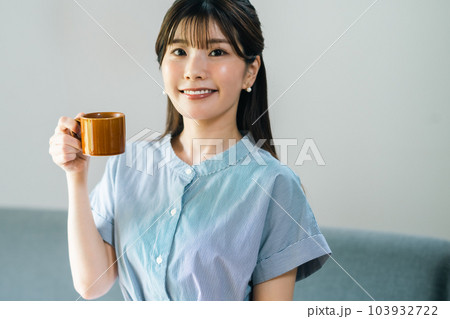 カフェでコーヒーを楽しむワンピース姿の若い女性 103932722