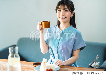 カフェでコーヒーを楽しむワンピース姿の若い女性 カフェでコーヒーを楽しむワンピース姿の若い女性 103932723