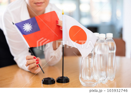 Little flag of Japan on table and flag of Taiwan put next to it by young woman Little flag of Japan on table and flag of Taiwan put next to it by young woman 103932746