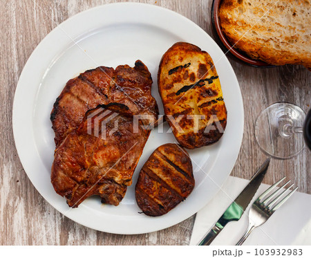 Fried pork on bone with grilled potatoes Fried pork on bone with grilled potatoes 103932983