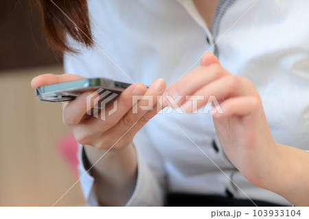 ベッドに座ってスマホを使用している女性　ビジネス 103933104