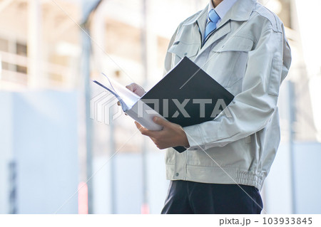 建設現場で書類を見る作業服の男性 103933845