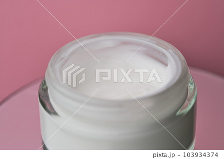 Glass jar with white face cream moisturiser on pink background. Glass jar with white face cream moisturiser on pink background. 103934374
