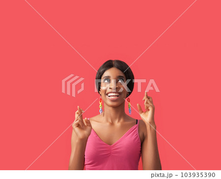 Good luck. Wish gesture. Opportunity chance. Inspired happy curious cheerful woman with crossed fingers looking up at empty space isolated on pink advertising background. 103935390