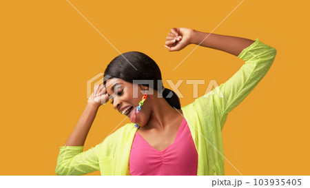 Happy dance. Fun joy. Positive lifestyle. Excited amused carefree smiling woman enjoying freedom luck isolated on bright orange color empty space background. Happy dance. Fun joy. Positive lifestyle. Excited amused carefree smiling woman enjoying freedom luck isolated on bright orange color empty space background. 103935405
