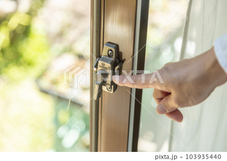 サッシのクレセント錠を締める女性 サッシのクレセント錠を締める女性 103935440